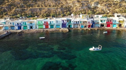 Aerial drone video from picturesque seaside village of Klima and traditional fishermen settlement with colourful boat garages called syrmata in island of Milos, Cyclades, Greece