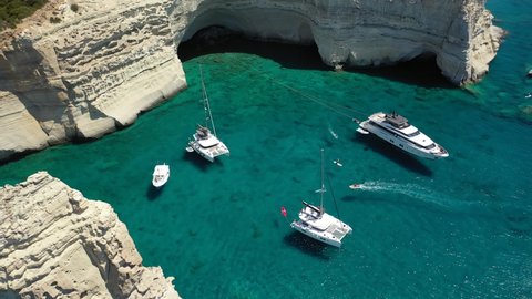 Arial drone video of Kleftiko a beautiful scenic white volcanic rock formation bay visited by sail boats and yachts with turquoise crystal clear sea and caves, Sea Meteora of Greece, Milos island
