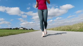 Slow motion 4K video of beautiful sporty young woman jogging in sportwear in the morning at sunny summer day