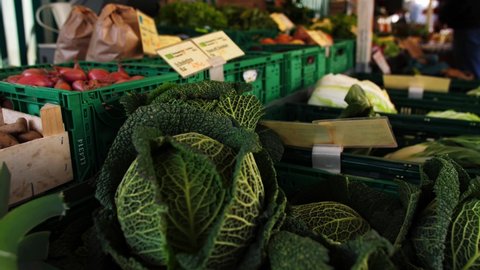 A closeup of the fresh cabbages and the leeks in the plastic crates in the market 4K