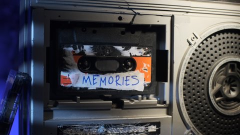 Close up footage dolly of old audio cassette with inscription MEMORIES. Concept of old time. best cassette in life plays on broken radio tape recorder.