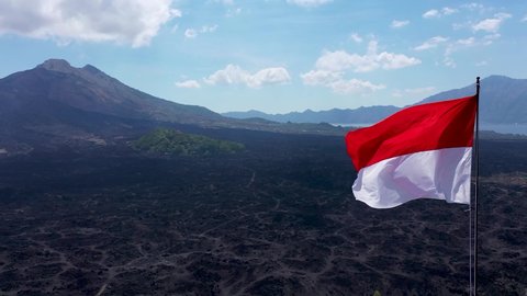Indonesian flag blowing in the wind at Batur volcano. The red and white Indonesian flag fluttering in the wind isolated on a blue sky background