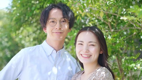 Smiling young asian couple in front of green plants.