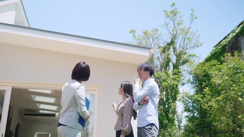 Young businesswoman showing house exterior for asian couple.