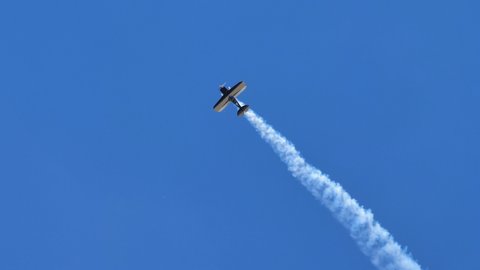Ferrara Italy JUNE, 27, 2021 Beautiful 4k high quality video of a retro biplane plane flying in the blue sky with white smoke trail. Christen Pitts S-2B Special