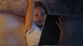 Girl does winner gesture and presses key on tablet in bed