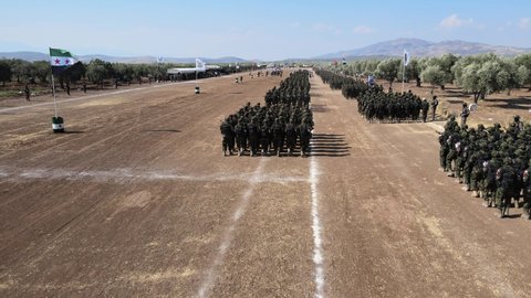 Afrin, Aleppo, Syria, July 6, 2021 Syrian fighters march in columns, ride dirt bikes and and drive pick-up trucks during a graduation ceremony near the northern city of Afrin for new recruits joining