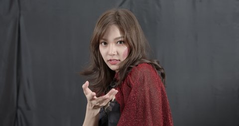 Mysterious Asian woman in witch cosplay make a spell and look at camera. Halloween party celebration around the world. Sexy and seductive girl in fantasy costume concept