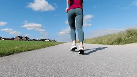 60 fps 4K video of beautiful sporty young woman jogging in sportwear in the morning at sunny summer day