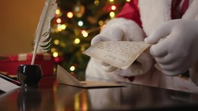 Santa Claus holding letter with wishes from  child in hands and reads his close-up at his desk on Christmas Eve or New Year's. - Powered by Shutterstock - Get 15% off with code: PIKWIZARD15