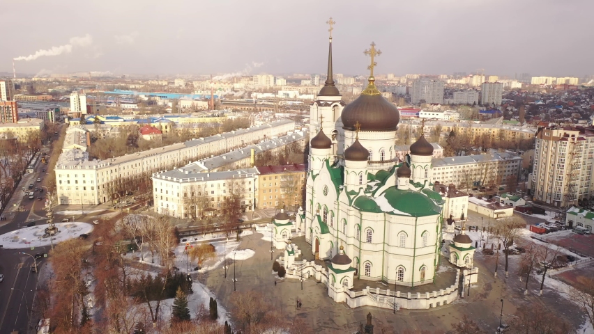 Aerial view of five-domed building of Annunciation Cathedral with attached bell tower in Voronezh on background with winter cityscape, Russia Royalty-Free Stock Footage #1078768883