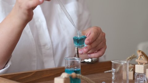Close-up of a pipette with oil and a glass bottle. woman pouring perfume in bottle. Perfume creating workshop