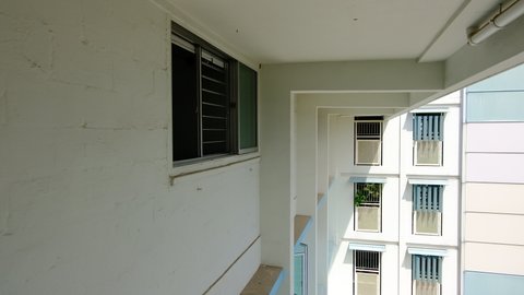 Person hanging Singapore flag outside HDB apartment window, to welcome national day