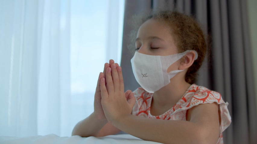 Little girl is praying in her room.Close up portrait of child concept faith religion and happy family.Child daughter crossed her arms, praying to god.Catholic pray worship and gratitude.