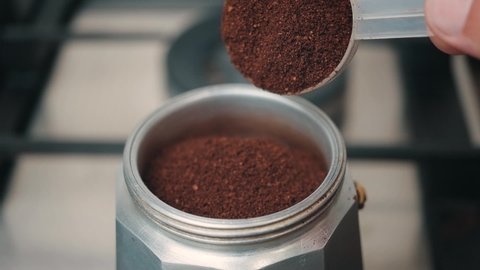 Process of making coffee in a geyser coffee maker, scoop with ground coffee, slow motion, close-up view