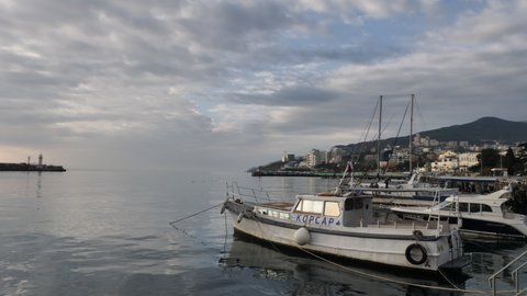 YALTA, RUSSIA-CIRCA2021: Vessels on water surface in front of a Yalta cityscape and a mountain against a sky by winter day.