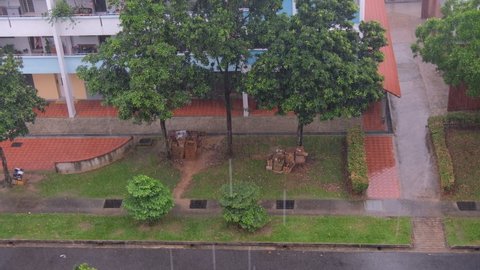 Top angle view of heavy falling rain outside, torrential downpour at heartland neighbourhood. HDB flat and trees in background. Rainy season in Singapore.