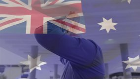 Animation of flag of australia waving over man wearing face mask during covid 19 pandemic. global covid 19 pandemic concept digitally generated video.