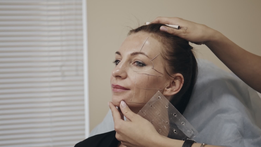 Plastic surgeon drawing correction lines on womans face. Doctor performing nesessary procedure, preparation before upcoming surgery. Concept of beauty, cosmetology. Royalty-Free Stock Footage #1078795610
