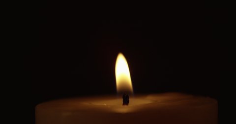 A candle flame blows in the wind and flickers in slow motion