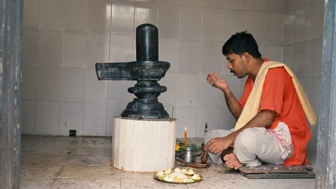 Howrah, West Bengal, India - 26th October 2020 : Hindu priest worshipping lord Shiva by offering prayers to Shiv Linga, inside a Shiva Temple. Lord Shiva is most worshipped Hindu God in India.