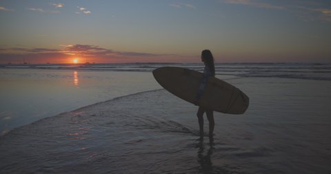 Slow Motion Shot Of Female Tourist With Surfboard Looking At Boats In Sea During Sunset - Tamarindo, Costa Rica