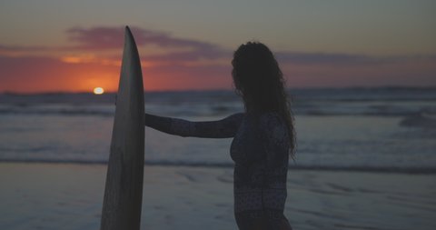 Slow Motion Shot Of Wet Female Tourist With Surfboard Looking At View Of Sunset At Beach During Vacation - Tamarindo, Costa Rica