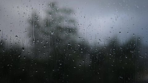 Raindrops on dark rainy through view of window medium slow motion shot