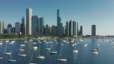 4K aerial Chicago harbor yacht club, USA water travel business footage. Blue lake waters panorama with scenic Chicago downtown cityscape on background. Waterfront buildings with Michigan lake view