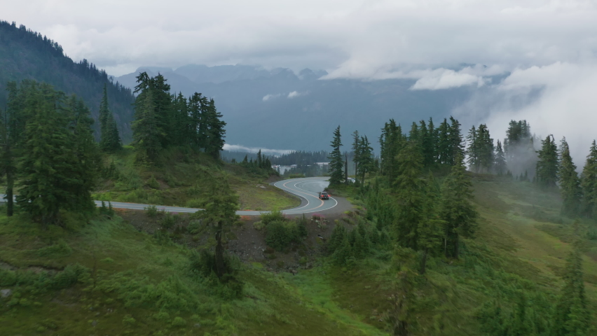 Beautiful nature of Northwest of USA and southwest of Canada. Car driving by the winding and curving mountain road with 180 turns. Aerial 4K footage road in foggy green forest covered by cloudy mist Royalty-Free Stock Footage #1078803572