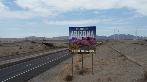 Ehrenberg, AZ USA - JULY 2, 2021: 4k Drone Tilt Jib Shot of Arizona Welcome Sign from California Highway Interstate 10 Freeway with Trucks Cars and Blue Cloudy Skies