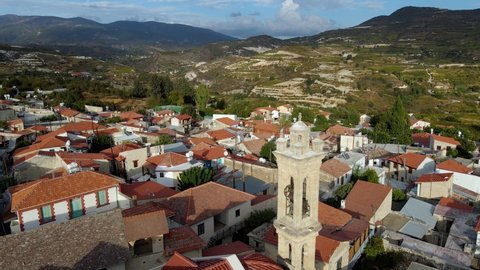 Aerial view around a bell tower, church and town, in sunny Cyprus - orbit, drone shot