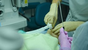 Immersion patient child in anesthesia, little girl with oxygen mask to perform surgical treatment. Anesthesiologist in medical gloves prepares kid for surgery. Resuscitation in hospital. 4 k video