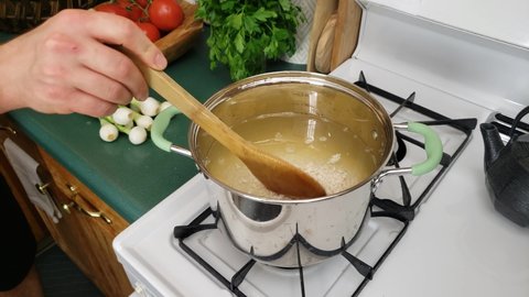 Home cooking - Pouring chicken stock or broth into pot and then adding white rice to be cooked on gas stove.