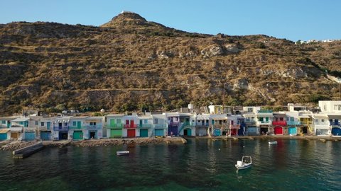 Aerial drone pan video from picturesque seaside village of Klima and traditional fishermen settlement with colourful boat garages called syrmata in island of Milos, Cyclades, Greece