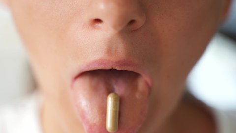 Close up shot of woman mouth with vitamin capsule. Micro dosing for depression treatment. Vitamins and supplements preventive medicine