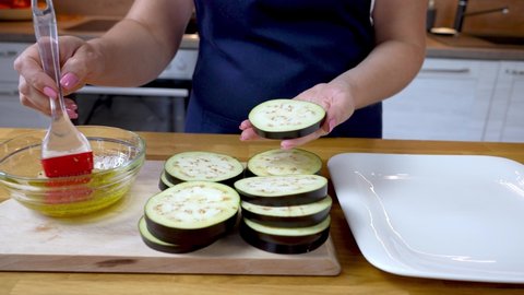 the cook greases the sliced eggplant with the seasoned olive oil sauce with a silicone brush. close up