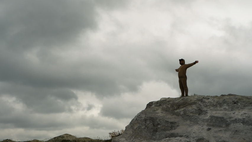 Happy man on the top of the mountain with his arms outstretched. The man imitates flight