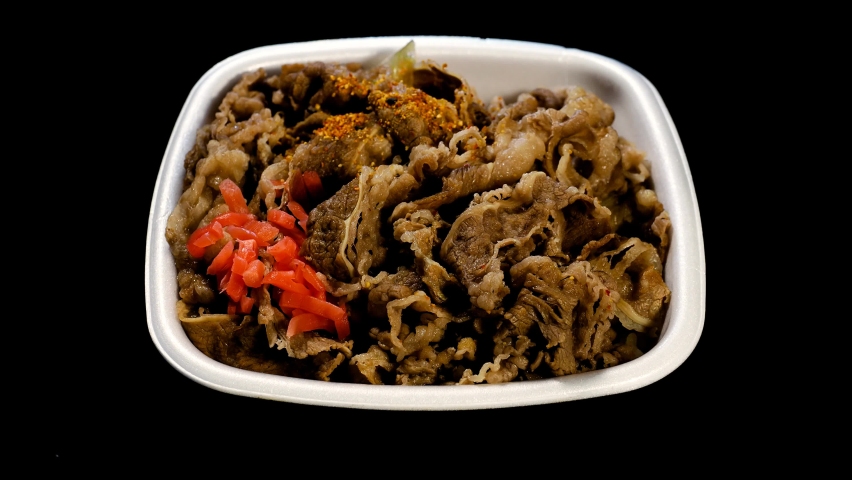 Closeup of beef bowl or gyudon in Styrofoam cup on black background
