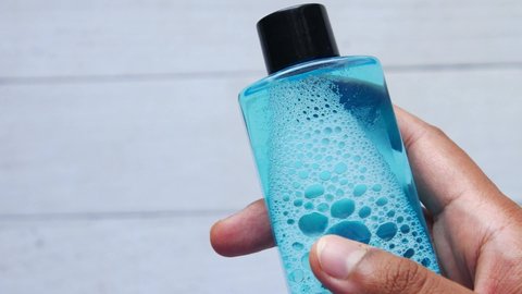 holding a container of mouthwash liquid 