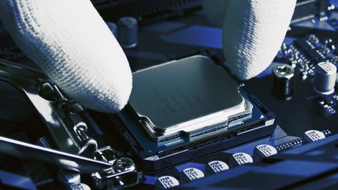 Minsk, Belarus - Oct 15, 2018: Six-core Intel Core i7 8700K processor installed and removed from computer motherboard CPU socket by technician in white antistatic gloves.