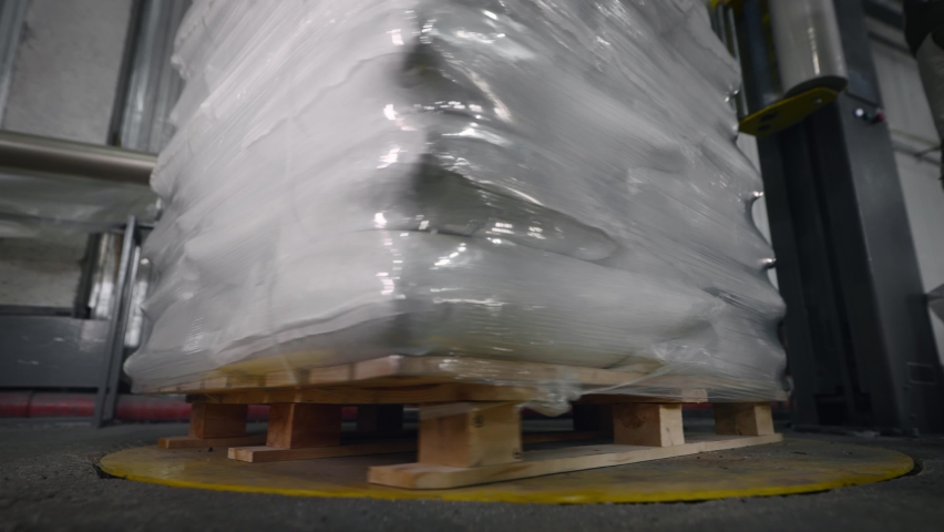 A pallet with bags is packed in foil using a special machine. Royalty-Free Stock Footage #1078821392