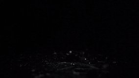 Water drops falling in black low light in slow motion close-up