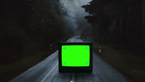 Old TV Green Screen On Spooky Dark Road, Vintage Television Traveling Shot. Vintage television with a green screen left on a spooky dark road. Traveling shot: film stockowy