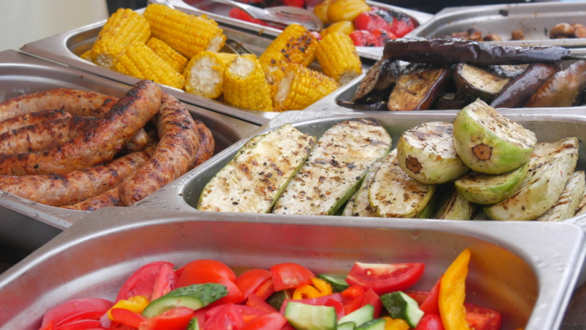 Grilled corn, sausage, eggplant and zucchini counter at outdoor street food festival. BBQ Shop for sale at the food festival. Street food ideas.