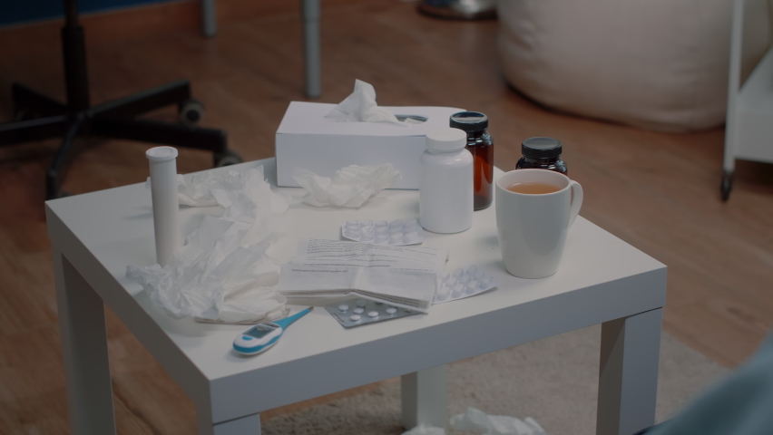 Close up of table with treatment and medical tools against disease. Empty space with medicaments, bottles of pills, capsule tablets, thermometer, tissues and tea. Medication against illness