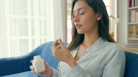 Woman take medicine and Drinking a Glass of Water. focus on the pill bottle. She had a headache and had the flu. health care concept