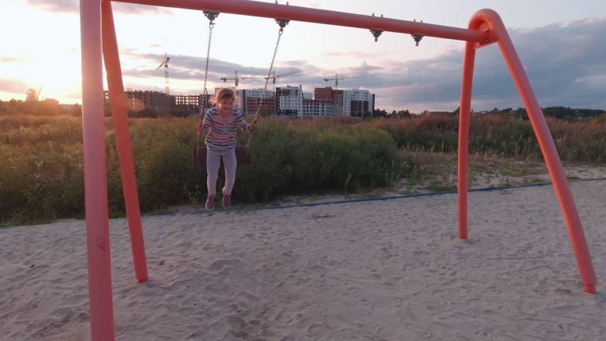 Girl on swing jumps sunset outdoors