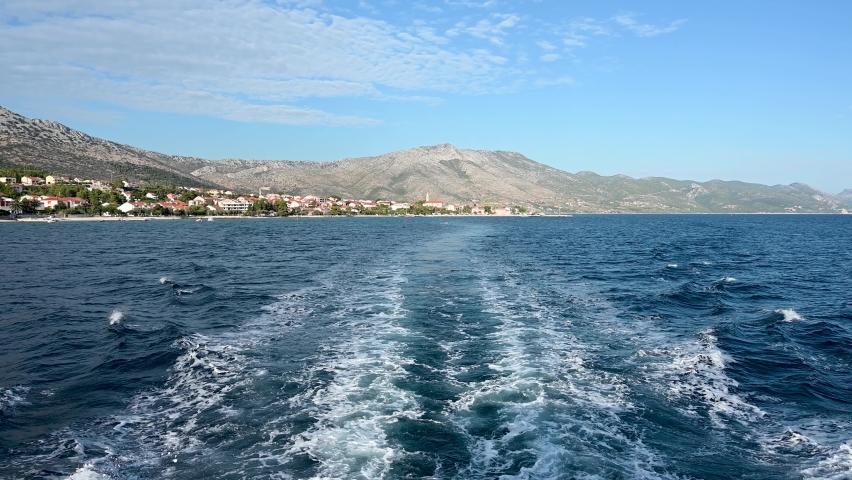 Peljesac peninsula, Dalmatia, Adriatic sea, Croatia. Wake of cruise ship on the sea. Speed boat on blue water splashing water and breaking the waves. Ferry boat cruising. 