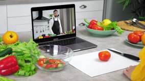 Woman in home kitchen study online video call webcam laptop listen chef slices tomato on cutting board tells teacher. Man food blogger in computer screen teaches housewife remote cooking course lesson